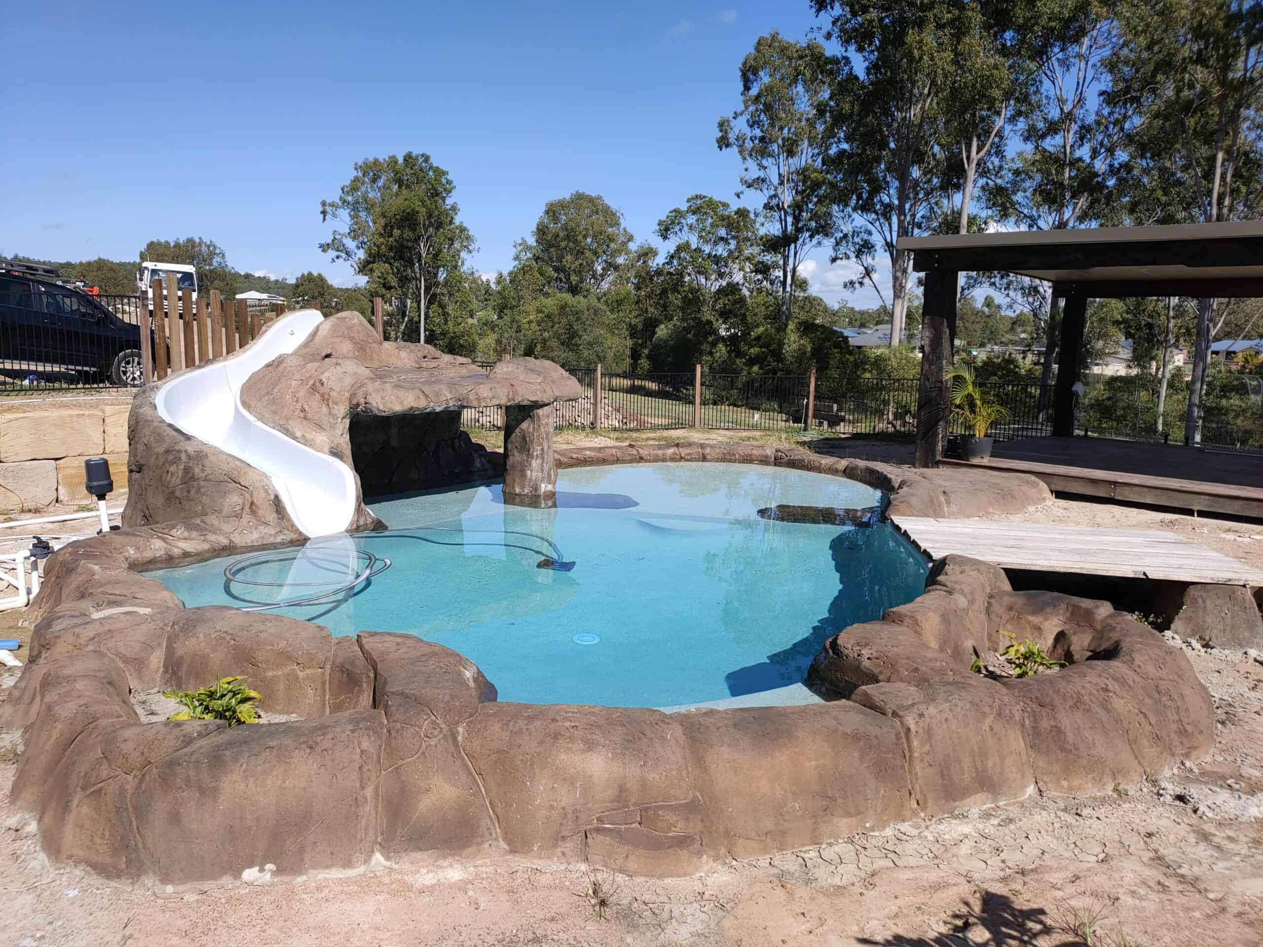 an outdoor swimming pool structure built into a rock structure with a slide