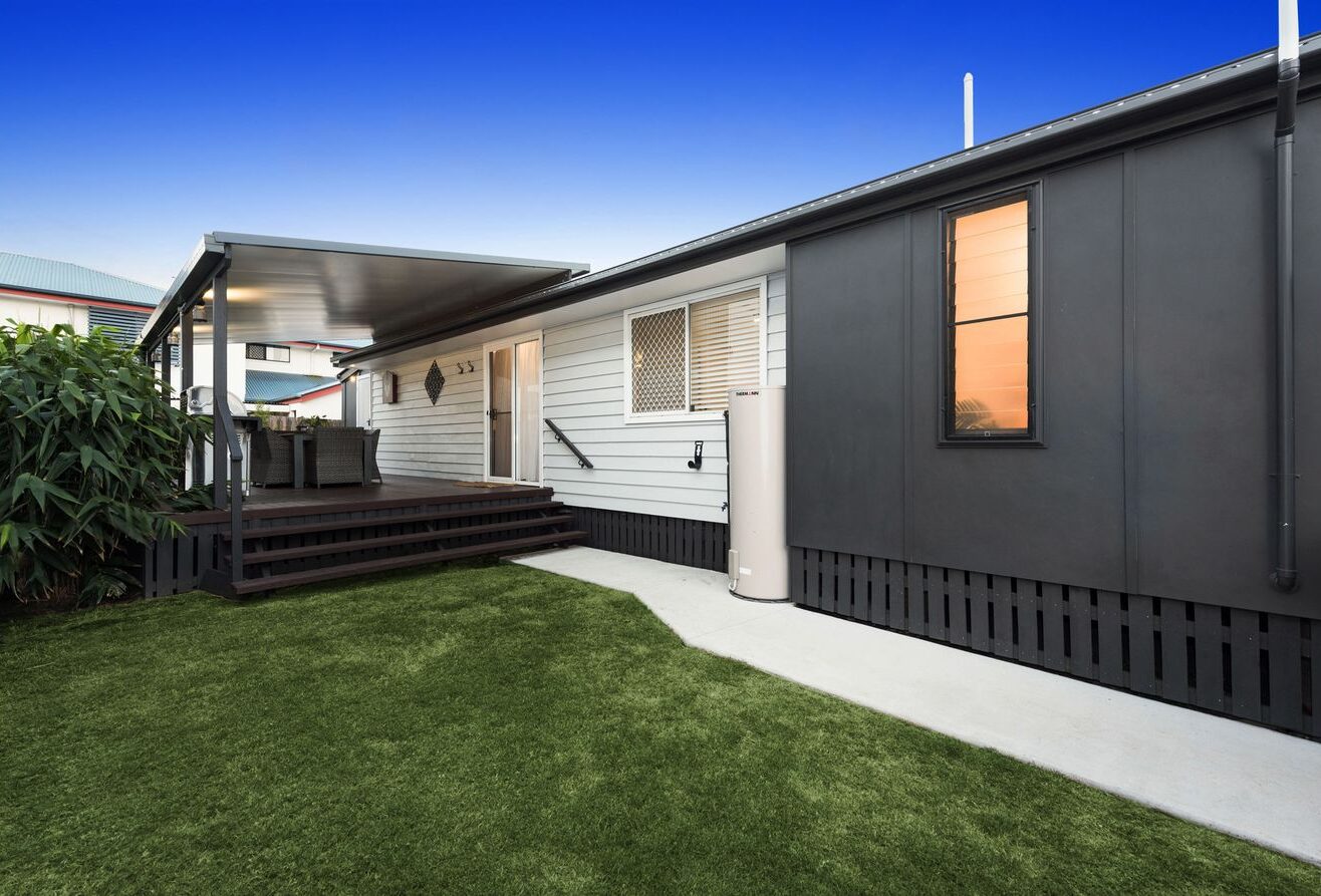 The side of a building in Australia with a black and a white wall as well as steps up to an outdoor seating area